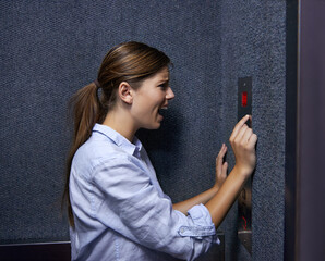 Is anyone out there. Shot of a fearful woman shouting into an elevator intercom. © Jeff Bergen/peopleimages.com