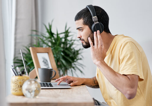 The Best Noise Cancelling Headphones In The Business. Shot Of A Young Man Using A Laptop And Headphones While Working From Home.