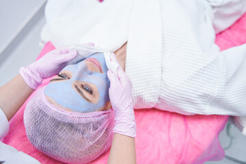 Cosmetician using damp facecloths for mask removal