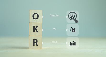 OKR text (Objectives, Key and Results) wooden cube block on grey background. Business target and...
