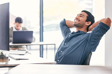It feels good to be done for the day. Shot of a handsome young businessman sitting in the office with his arms behind his head in relief.