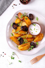 Roasted potato wedges with mushrooms and spices served with yogurt sauce topped with microgreen. Hot meal. Top view