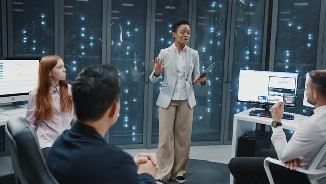Data center office. Young african businesswoman leading meeting with multi-ethnic staff coworkers. Server room database. Cyber security. Supercomputer.