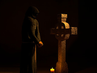 Christian monk with his head bowed, meditating in front of a cross of stone