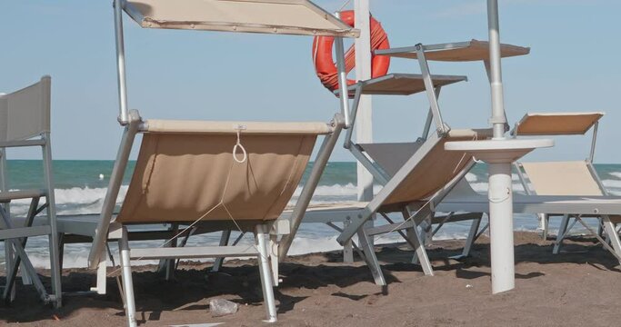 Empty beach chairs and sunbeds in front of the beach with rough seas