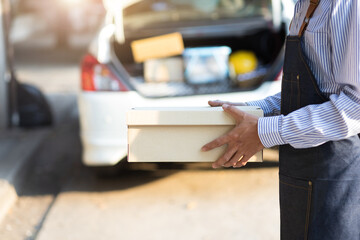 A postman or delivery man stands holding a package while waiting for a customer to pick up the package.