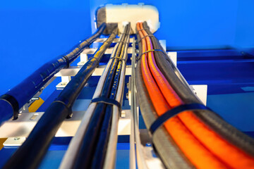 Electrical wiring. Orange and black cables on blue background. Wires are secured with plastic ties....