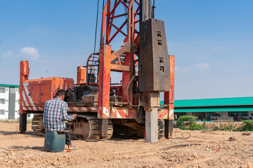 Pile driver machine hammering concrete pile and worker blow count