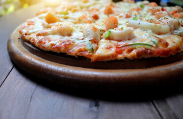 Slice of hot pizza large cheese lunch or dinner crust seafood meat topping sauce. with ham and crab stick delicious tasty fast food italian traditional on wooden board table classic in side view.