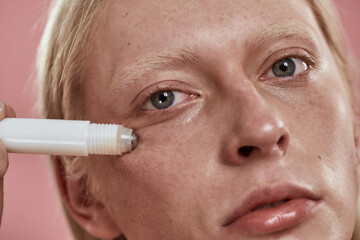 Partial of guy applying depuffing eye serum