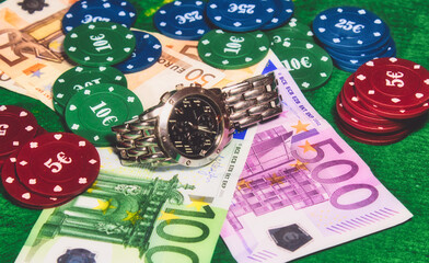 High roller stakes in a poker or card game with bank notes, casino chips and a wrist watch