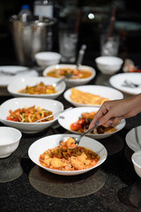 Hand using spoon scoop fried tofu and variety thai food on dining table