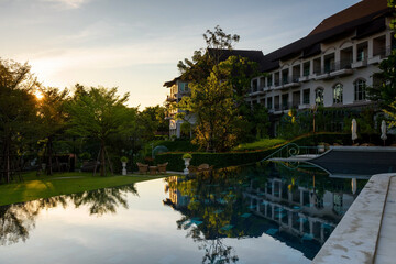 Fototapeta na wymiar Luxury hotel swimming pool and garden at sunrise