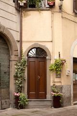 Fototapeta na wymiar Entrance, decorated with flower pots, wooden door. Street in the Italian town of Lovere