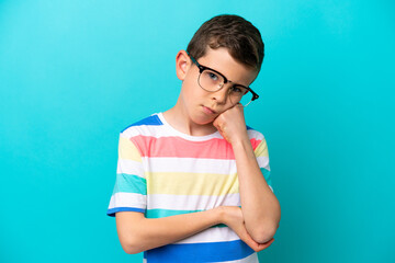 Little boy isolated on blue background With glasses and with sad expression