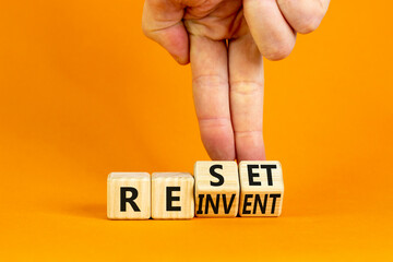 Reinvent and reset symbol. Businessman turns wooden cubes and changes the concept word Reinvent to...
