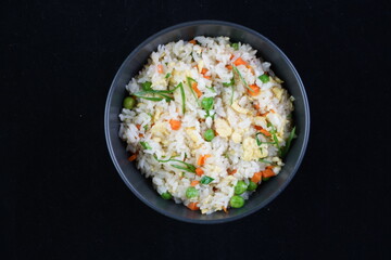 Veg Fried Rice in gray bowl on concrete table top. Veg Fried rice is indo chinese cuisine dish. Indian vegetarian meal. Asian food. Copy space. Top view