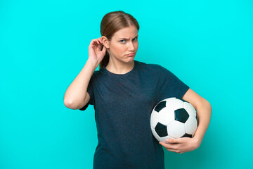 Young football player woman isolated on blue background having doubts