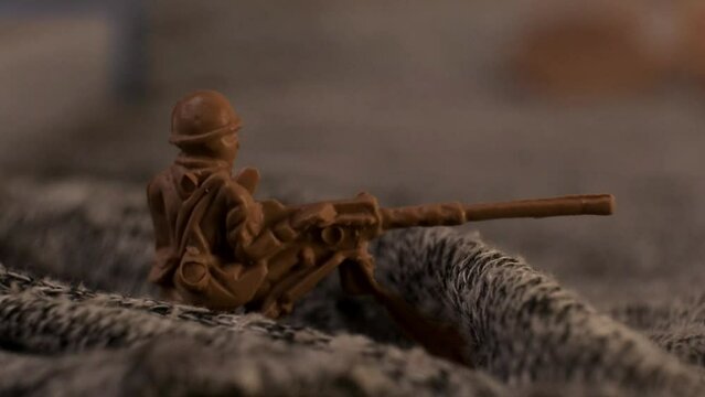 A toy plastic soldier machine gunner in an imaginary trench with flashing red light. The concept of shooting during the battlefield at night