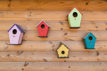 Obraz na płótnie Canvas Many bright colored birdhouse and bird feeders on wooden fence. Different birdhouses on wall