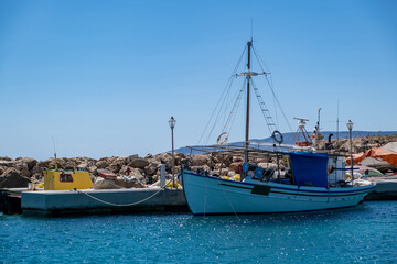 Fototapeta na wymiar Fishing boat moored at Koufonisi Greek island port dock. Cyclades, Aegean sea, blue sky background.