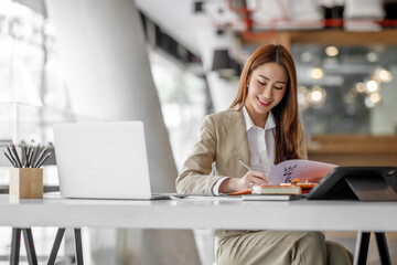 Fototapeta premium Portrait of Young Asian woman hand freelancer is working her job on computer tablet in modern office. Doing accounting analysis report real estate investment data, Financial and tax systems concept.