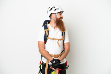 Young rock- climber reddish caucasian man isolated on white background looking side