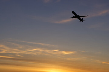 Airplane flying in the sky during sunset. Holidays and business travel concept.