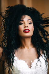 Beautiful african american woman posing at camera in white dress. Portrait of cheerful young woman with afro hairstyle. Beauty girl with curly hair.