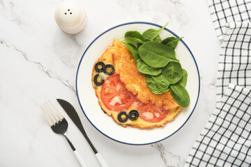 Omelette with tomatoes, black olives, cottage cheese and green spinach herbs on white plate on grey concrete background. Delicious breakfast. Healthy breakfast food. Top view.