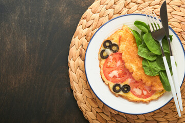 Omelette with tomatoes, black olives, cottage cheese and green spinach herbs on white plate on old wooden rustic dark background. Delicious breakfast. Healthy breakfast food. Top view.