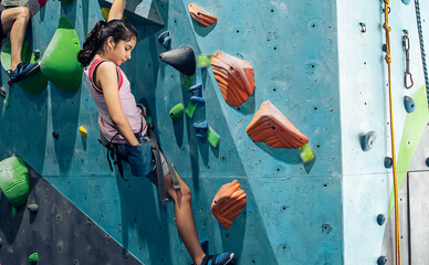 Caucasian active girl playing with happiness and climbing rock mountain with safety for adventure and sport. Activity and Education Concept. - obrazy, fototapety, plakaty