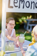 The perfect refresher on a hot summers day. Cropped shot of a little girl selling lemonade from her...