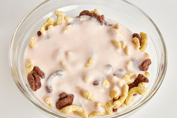 Yogurt is poured into a transparent bowl of granola on a white background. Healthy food. Baby food.