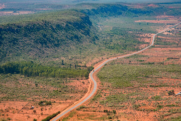 Aerial view of a shrub-covered ridge of the Great Rift Valley, paralleled by a main road leading...