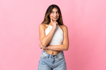 Young caucasian woman isolated on pink background thinking an idea while looking up