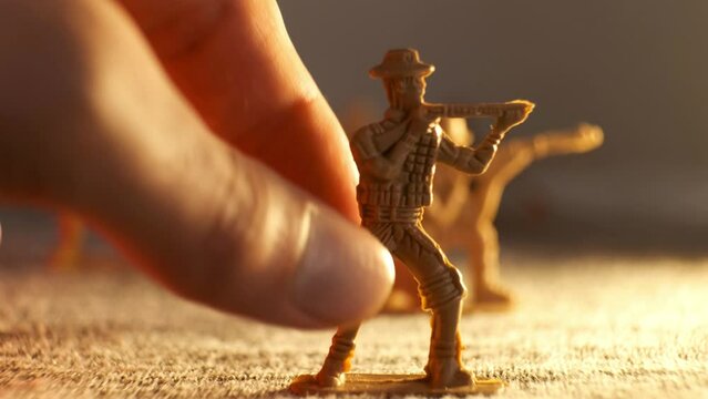 A human hand moves a toy soldier forward on an imaginary battlefield