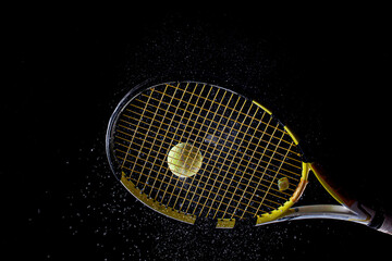 Tennis ball bouncing on racket. Dirt or magnesium dust dots visible in the air..