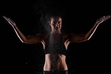 Obraz premium Kickboxer kirl with magnesium powder on her hands punching with dust visible..