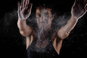 Kickboxer kirl with magnesium powder on her hands punching with dust visible..