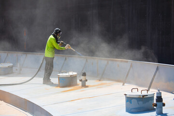 Male worker surface corrosion plate preparation by sand blasting of tank