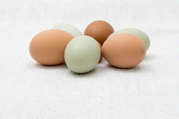 Rohe Eier von bunt legenden Hühnern, grün und braun, im Haufen auf grobem Leinen