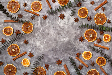Fototapeta na wymiar Flat lay composition of spices and dried fruits. Orange, cinnamon, star anise and eucalyptus sprigs on a gray background. Place for text. Natural Christmas composition. Festive background, postcard.