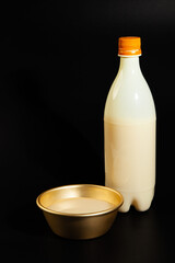 Makgeolli rice wine is a Korean fermented alcoholic beverage traditional drinks. 
Korean alcoholic drink (Makgeolli) in a traditional Korean gold liquor bowl with snack on Black background. 