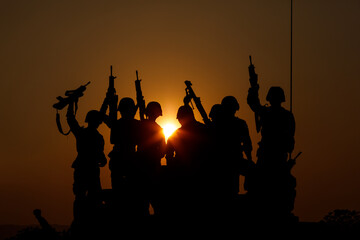 silhouette group of special forces sodiers hold the guns on tanks to indicative of their victory with the sunset background