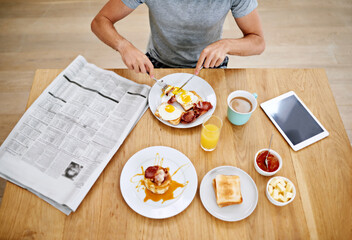 His morning routine. High angle shot of a man eating breakfast while reading the morning paper.