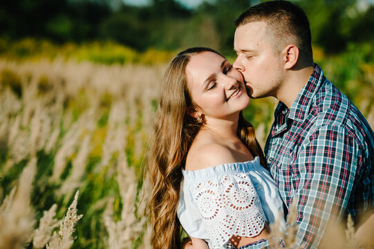 Couple hugging and kissing at sunset in spring outdoors. Family on grass background. Close Up. Place for text and design. selective focus.