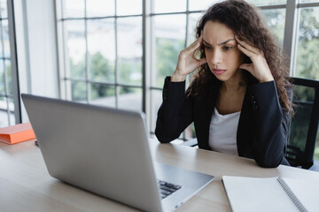 Young business woman suffering from headache in office