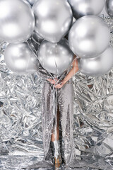 Beauty woman with silver chrom helium balloons on rumpled backdrop