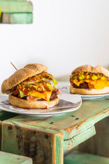Two cheeseburgers served on a green wooden shelf